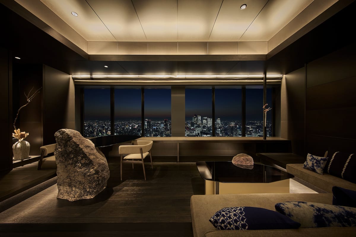 A modern interior with a city view, a large rock sculpture, and contemporary furniture.