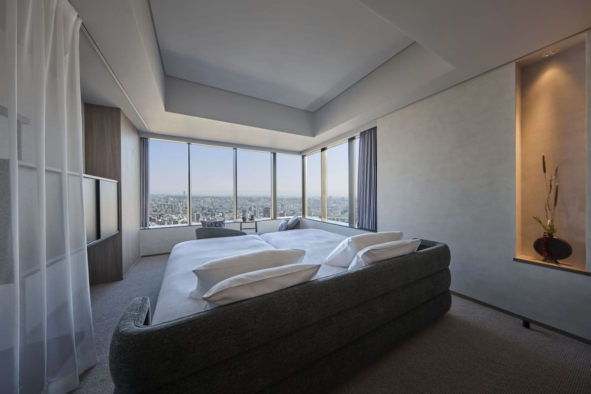 A modern hotel room with a large bed, a city view, and a skylight.