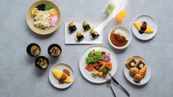 A variety of dishes including sushi, rice, and vegetables on a table.