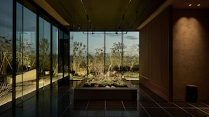A modern interior with a large glass wall, a central planter with rocks and plants, and a polished floor. - The Royal Park Hotel Iconic Nagoya (Nagoya)