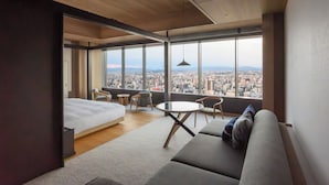 A modern hotel room with a large window, a bed, a sofa, and a small table. - The Royal Park Hotel Iconic Nagoya (Nagoya)