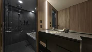 A modern bathroom with a glass-enclosed shower, a bathtub, and a vanity with two sinks.