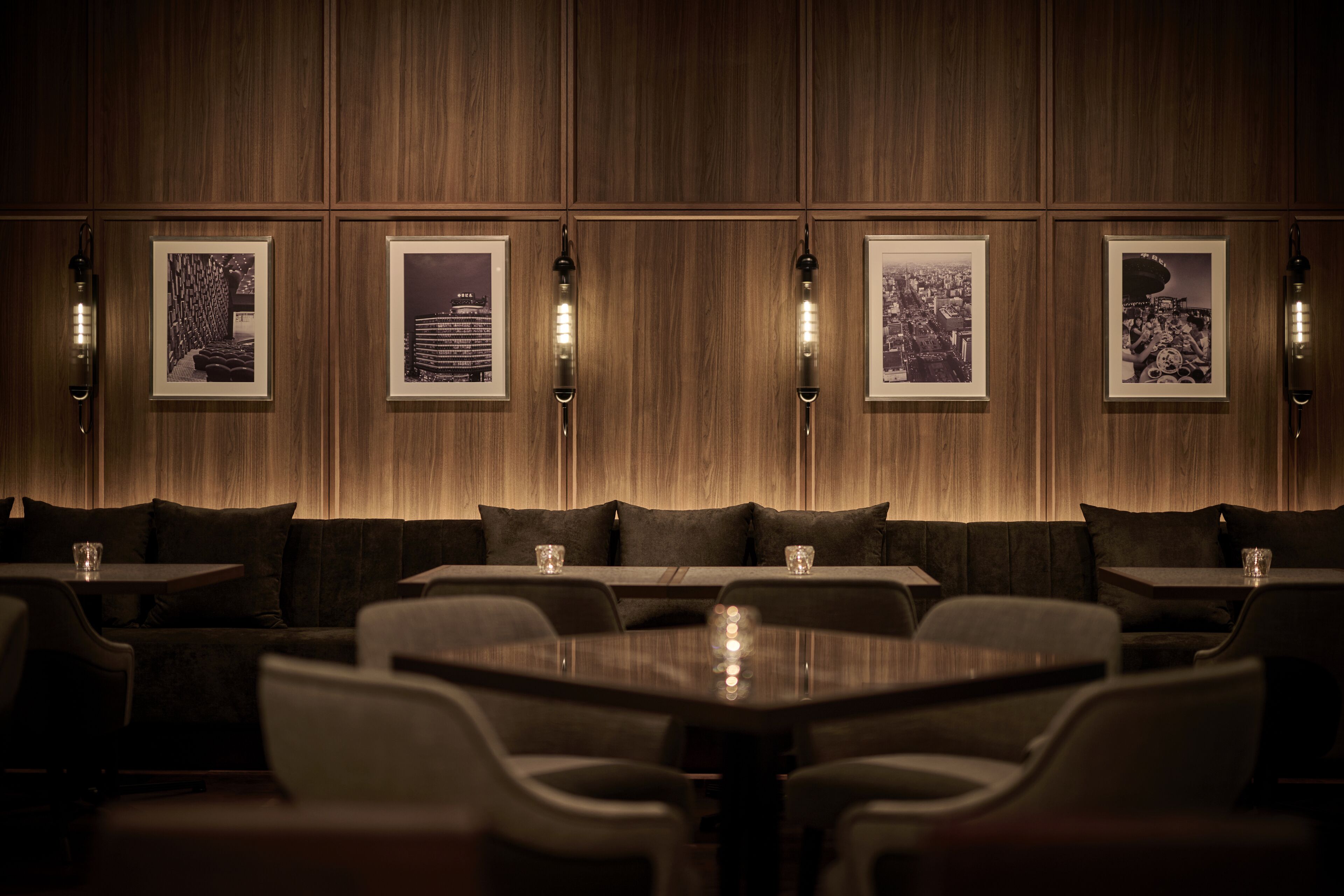 A dimly lit restaurant with wooden panel walls, framed pictures, and modern seating.