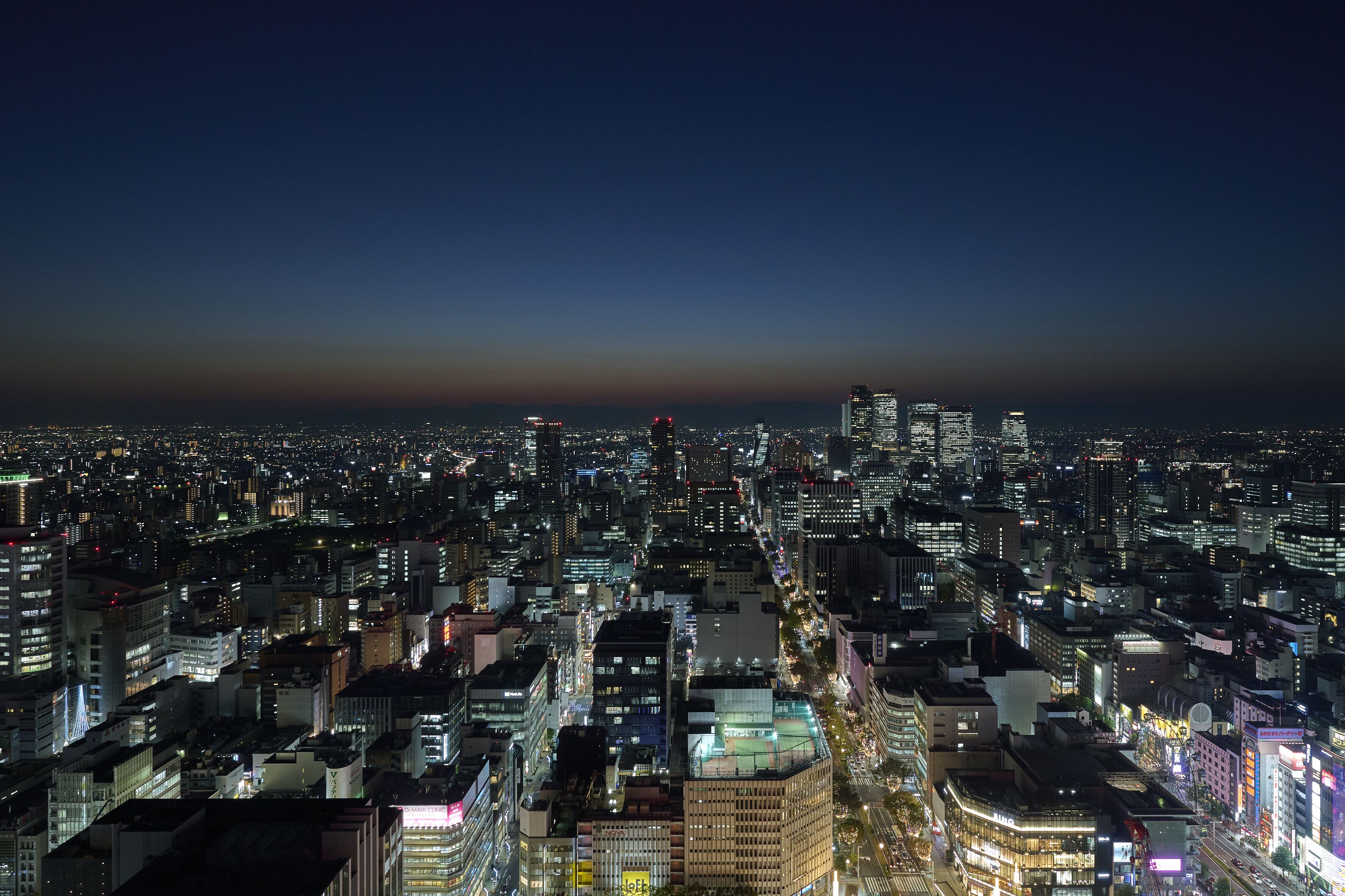 A nighttime cityscape with dense urban buildings and illuminated streets.