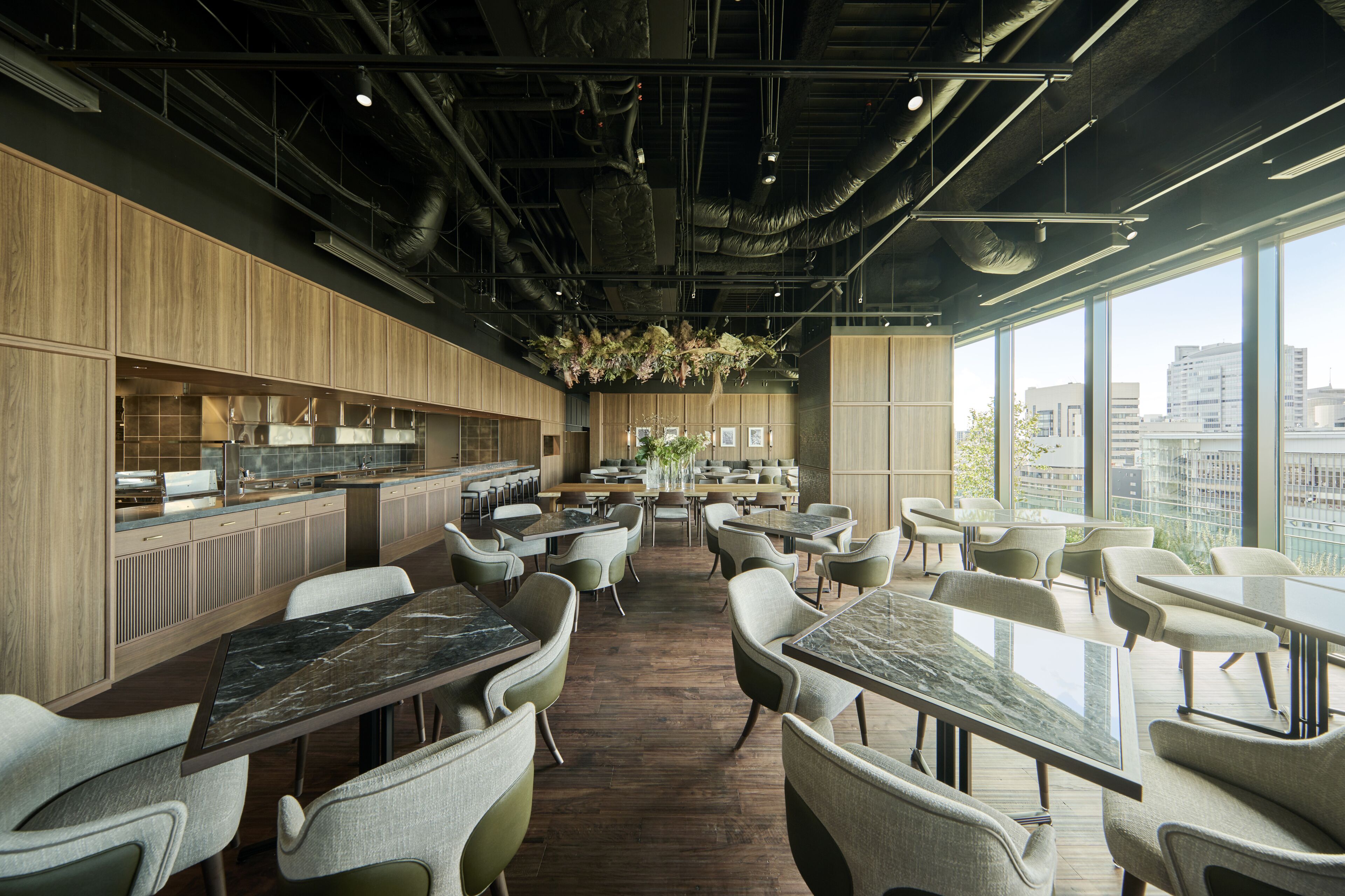 Un restaurant moderne doté d’un long comptoir, de plusieurs espaces de restauration et de grandes fenêtres offrant une vue sur la ville.
