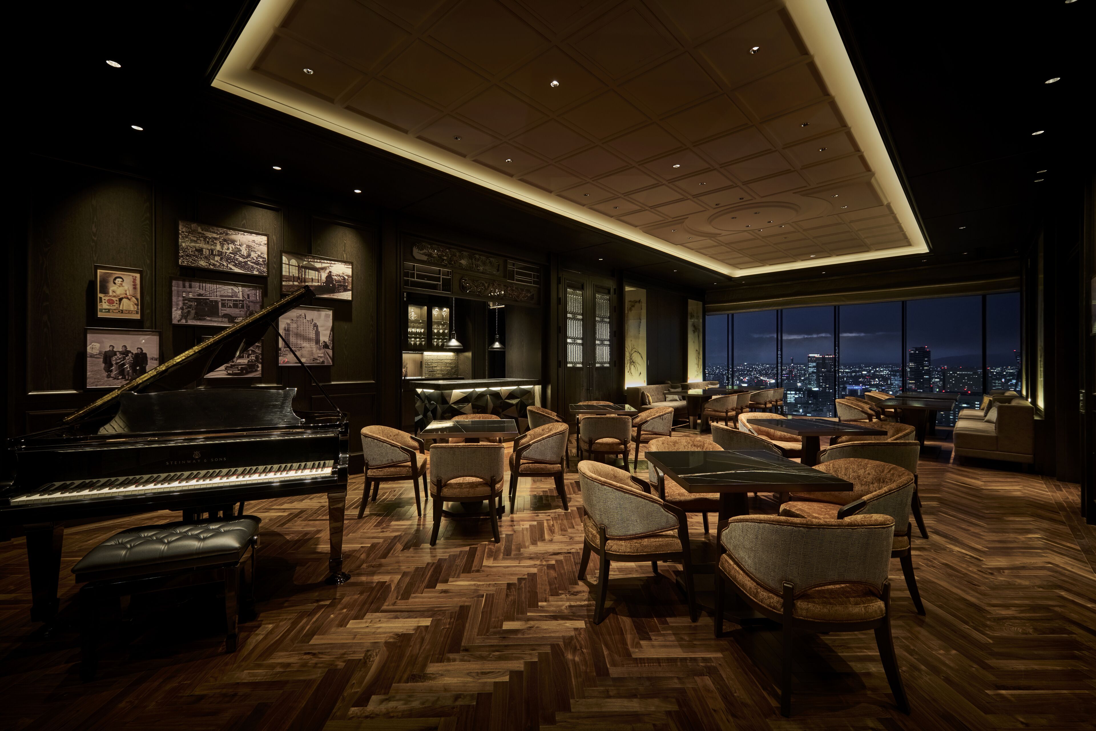 A spacious lounge with a grand piano, comfortable seating, and a city view.