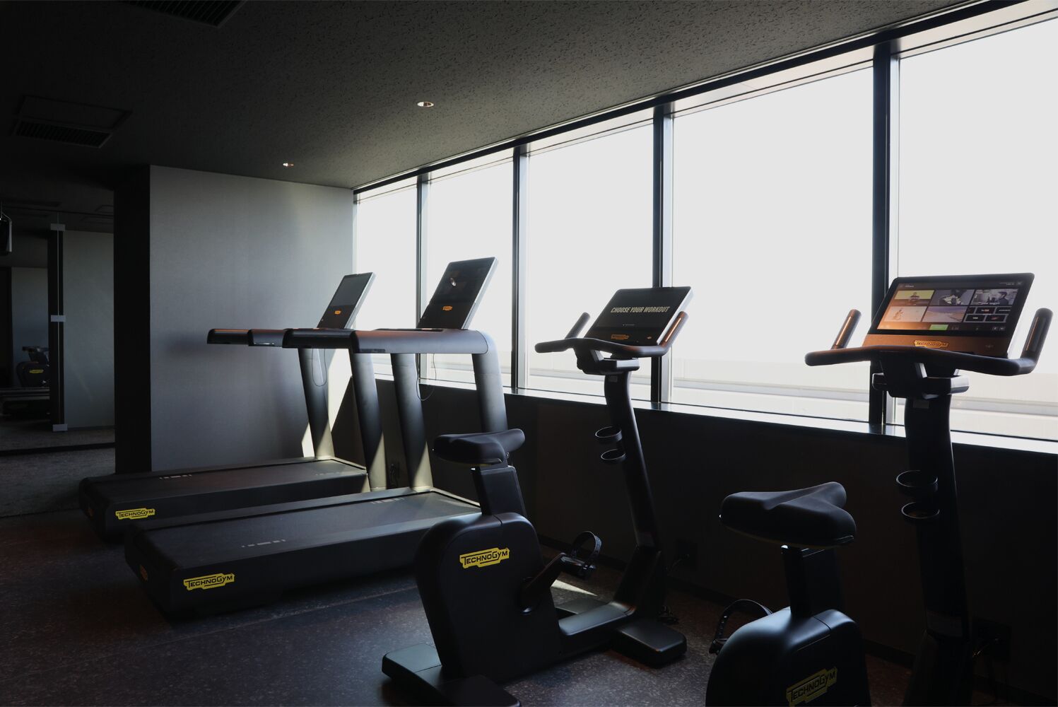 Une salle de sport équipée de tapis de course, d’un vélo elliptique et d’un vélo d’appartement, tous dotés d’écrans numériques.