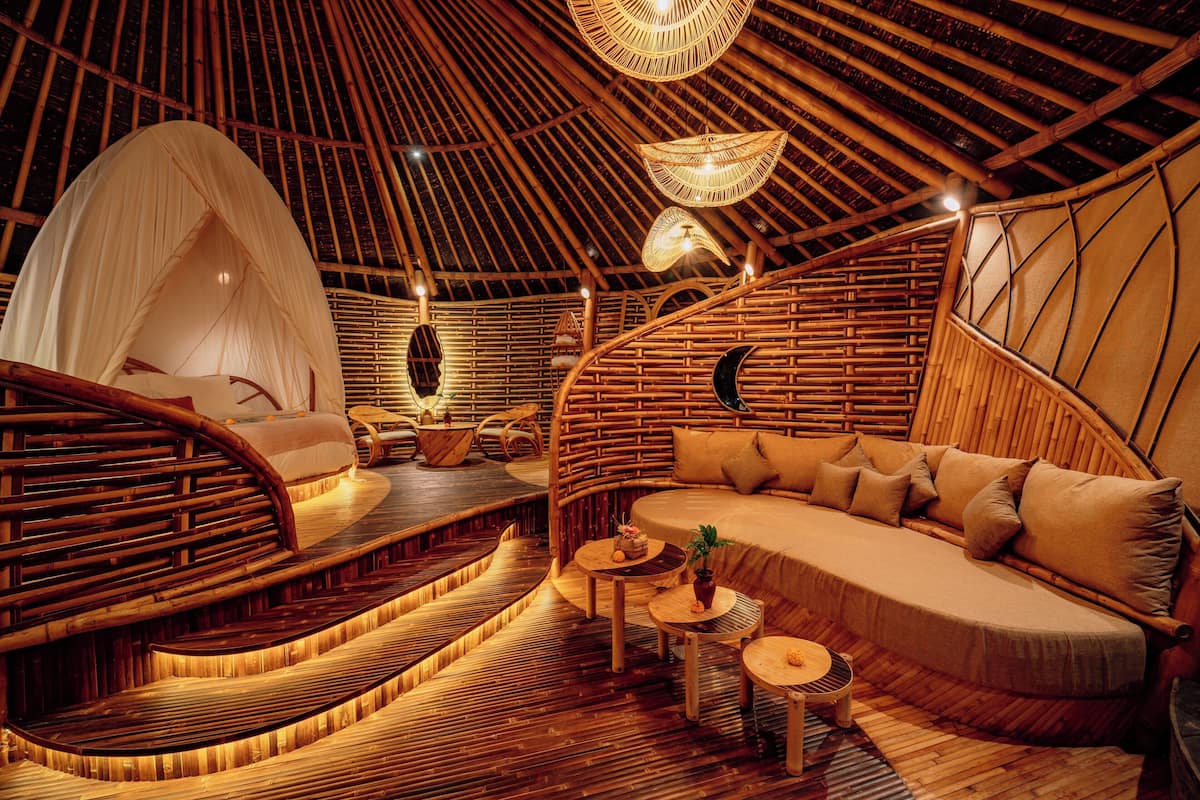 Une pièce circulaire et accueillante, dotée d’un toit de chaume, d’un coin salon confortable et d’une petite table agrémentée d’une plante.