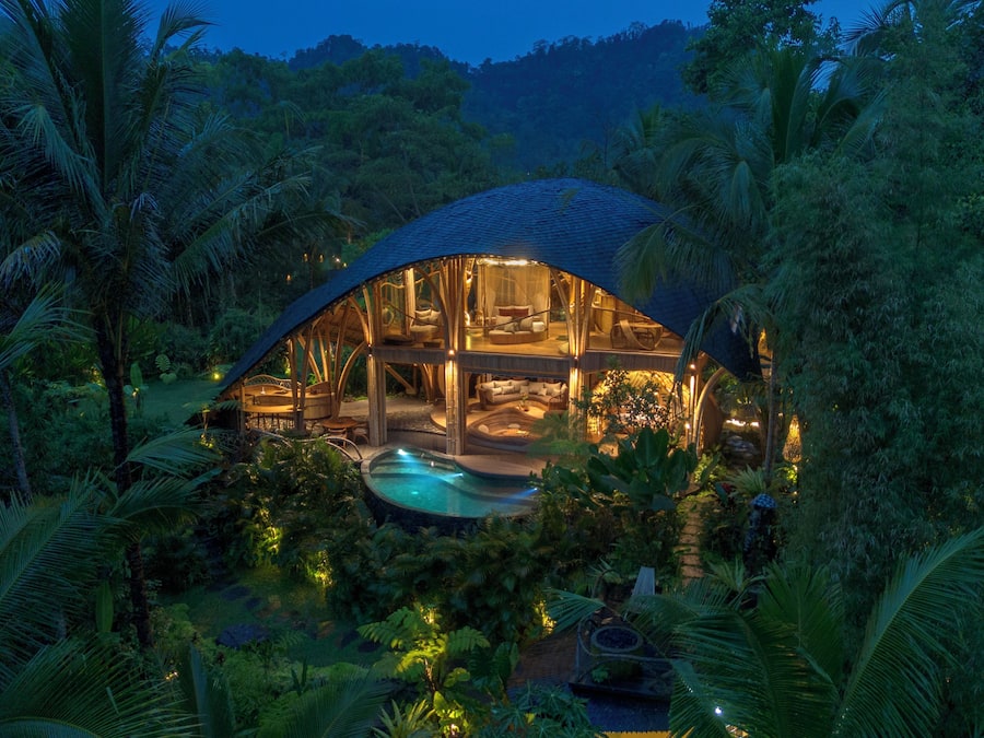 A dome-shaped building with a pool, surrounded by tropical vegetation.