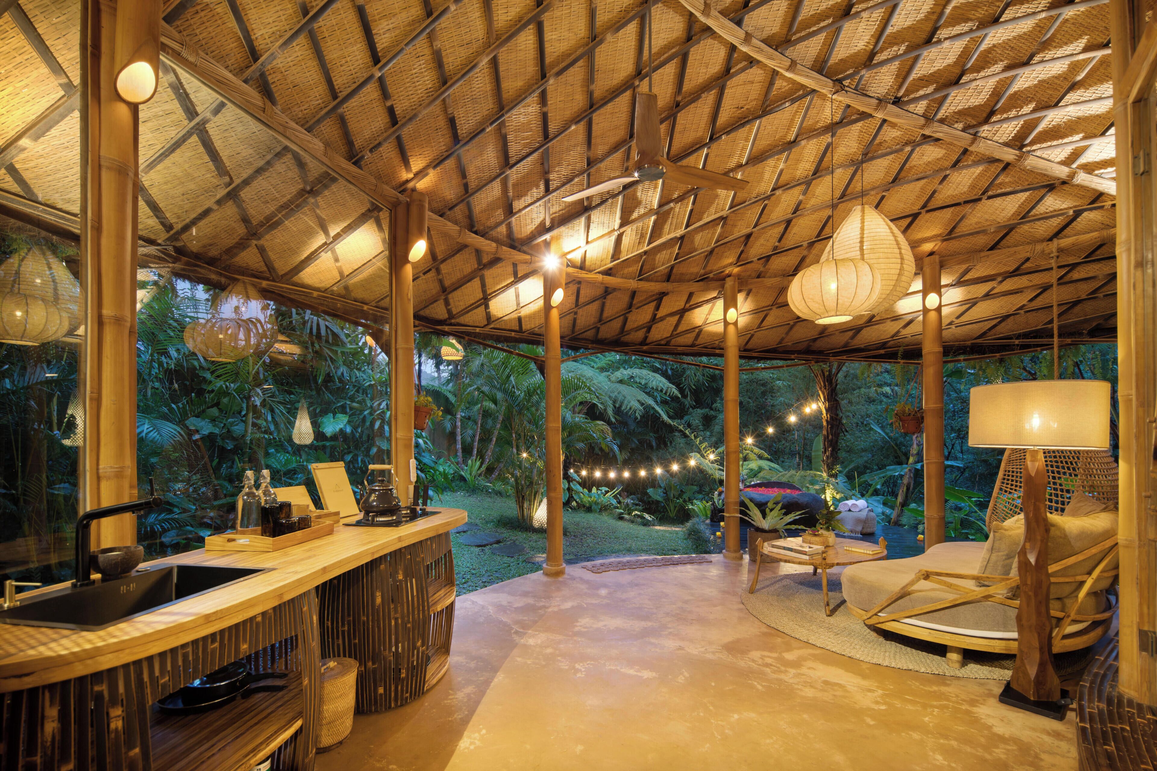 Un espace extérieur abrité comprenant un bar, des sièges et une vue sur un jardin luxuriant.