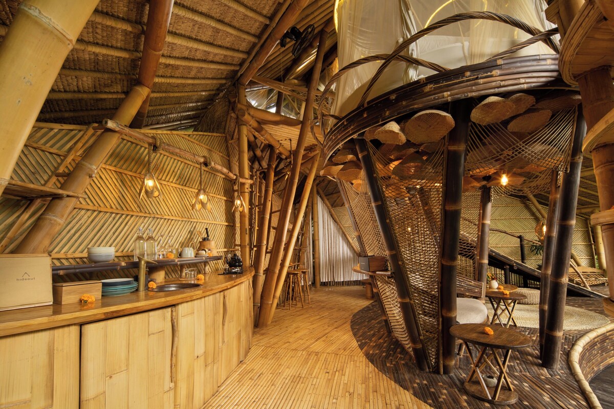 A bamboo-themed interior with a curved wooden counter, hanging light fixtures, and a woven ceiling structure.