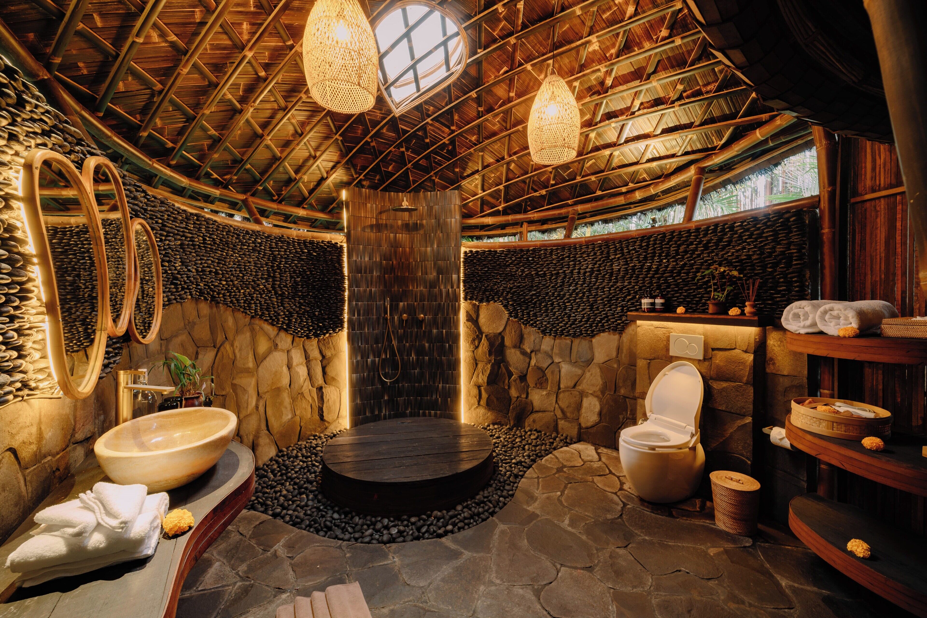 Un baño con paredes de piedra, una bañera de madera, un lavamanos grande y un inodoro.