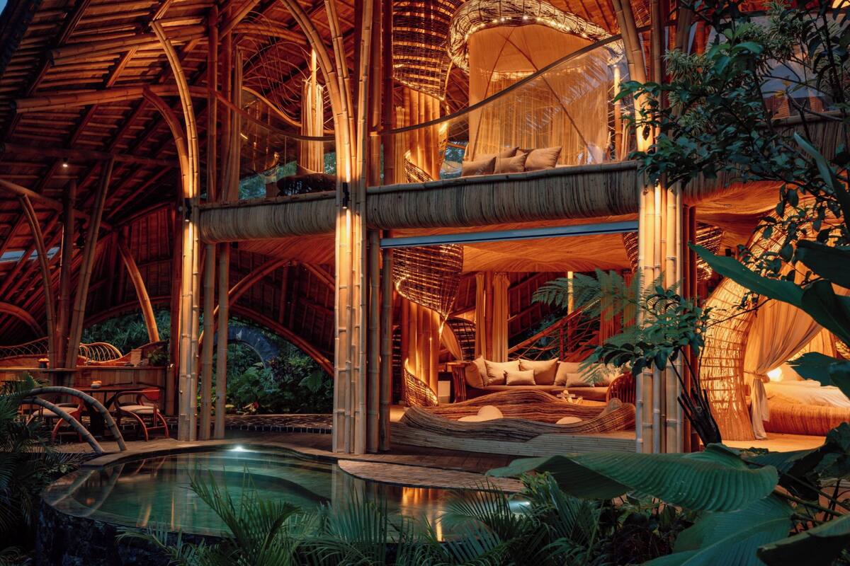 Une structure à plusieurs niveaux, faite de bambou, comprenant une piscine, des espaces de détente et un auvent.
