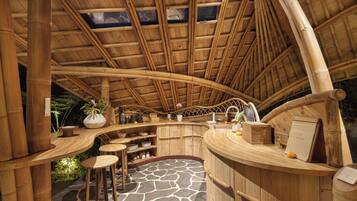 A bamboo-themed interior with a curved ceiling, a central bar area, and a stone-tiled floor.