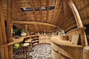 A bamboo-themed interior with a curved ceiling, a central bar area, and a stone-tiled floor.
