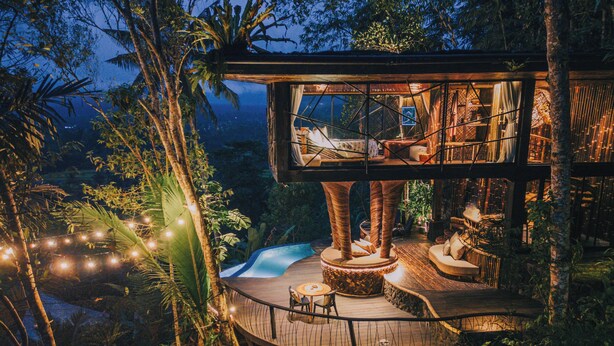 A treehouse with a wooden deck, a small pool, and a dining area. - Hideout Eco Bamboo House Bali (Selat)