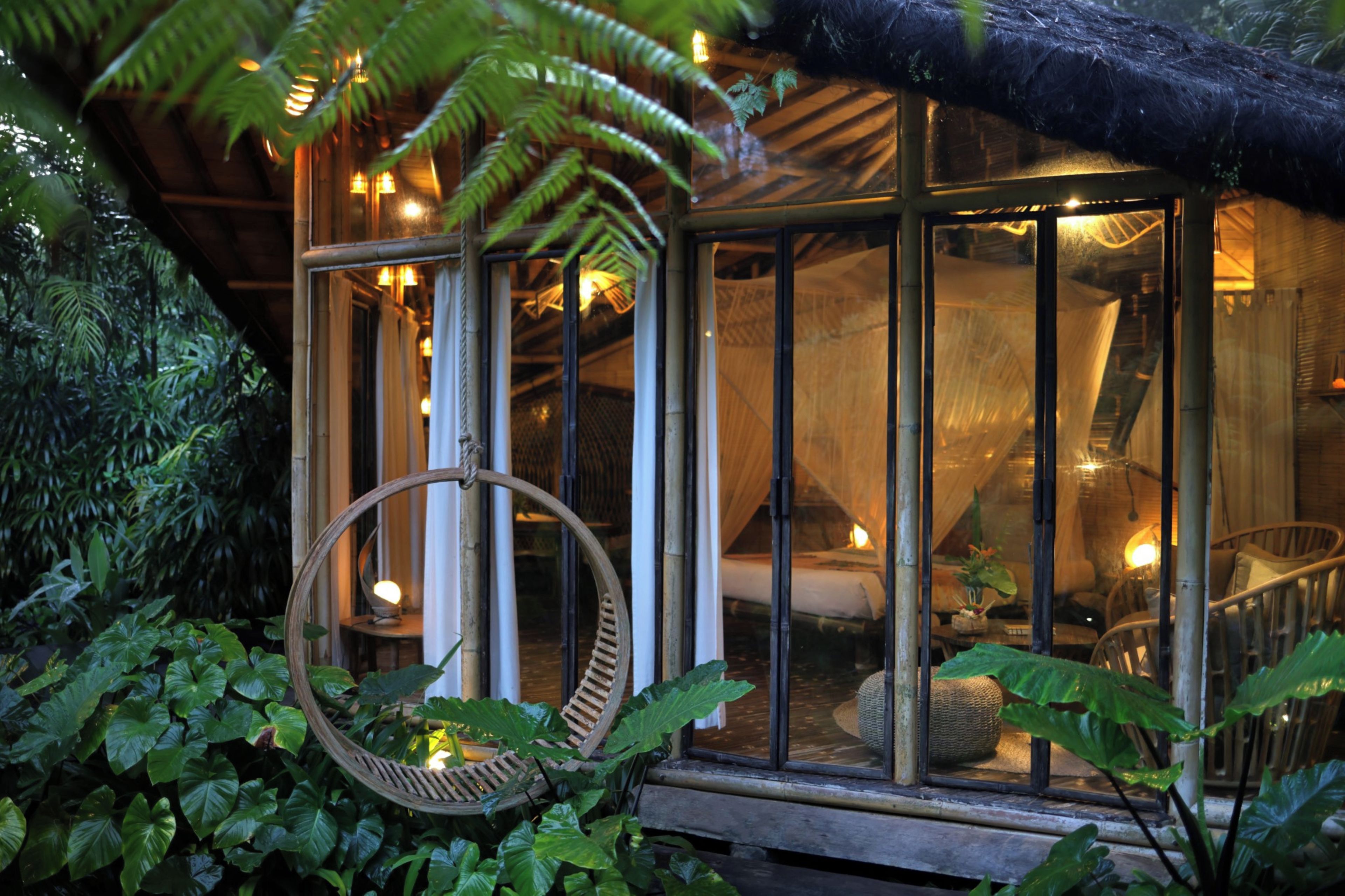 A rustic wooden structure with a glass enclosure, surrounded by lush greenery.