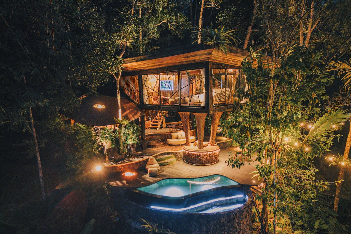 Une cabane dans les arbres avec une piscine, entourée d’une végétation luxuriante.