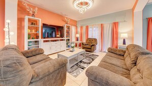 A living room with a sofa set, a coffee table, and a television. - Affordable Luxury 4 BR Villa, Close to Disney & Orlando, Pool/Spa, Arcade Games. (Clermont)
