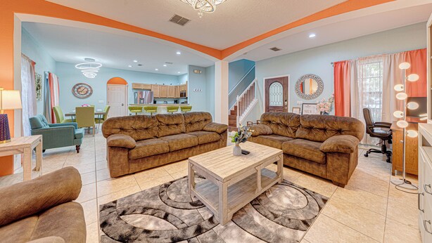 A spacious living room with two brown sofas, a wooden coffee table, and a chandelier. - Affordable Luxury 4 BR Villa, Close to Disney & Orlando, Pool/Spa, Arcade Games. (Clermont)