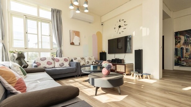 Una sala moderna con un sofá gris, una mesa de centro redonda y un televisor de pantalla plana montado en la pared.