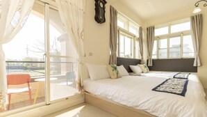 Un dormitorio con una cama grande, una puerta corrediza de vidrio a un balcón y un reloj en la pared.