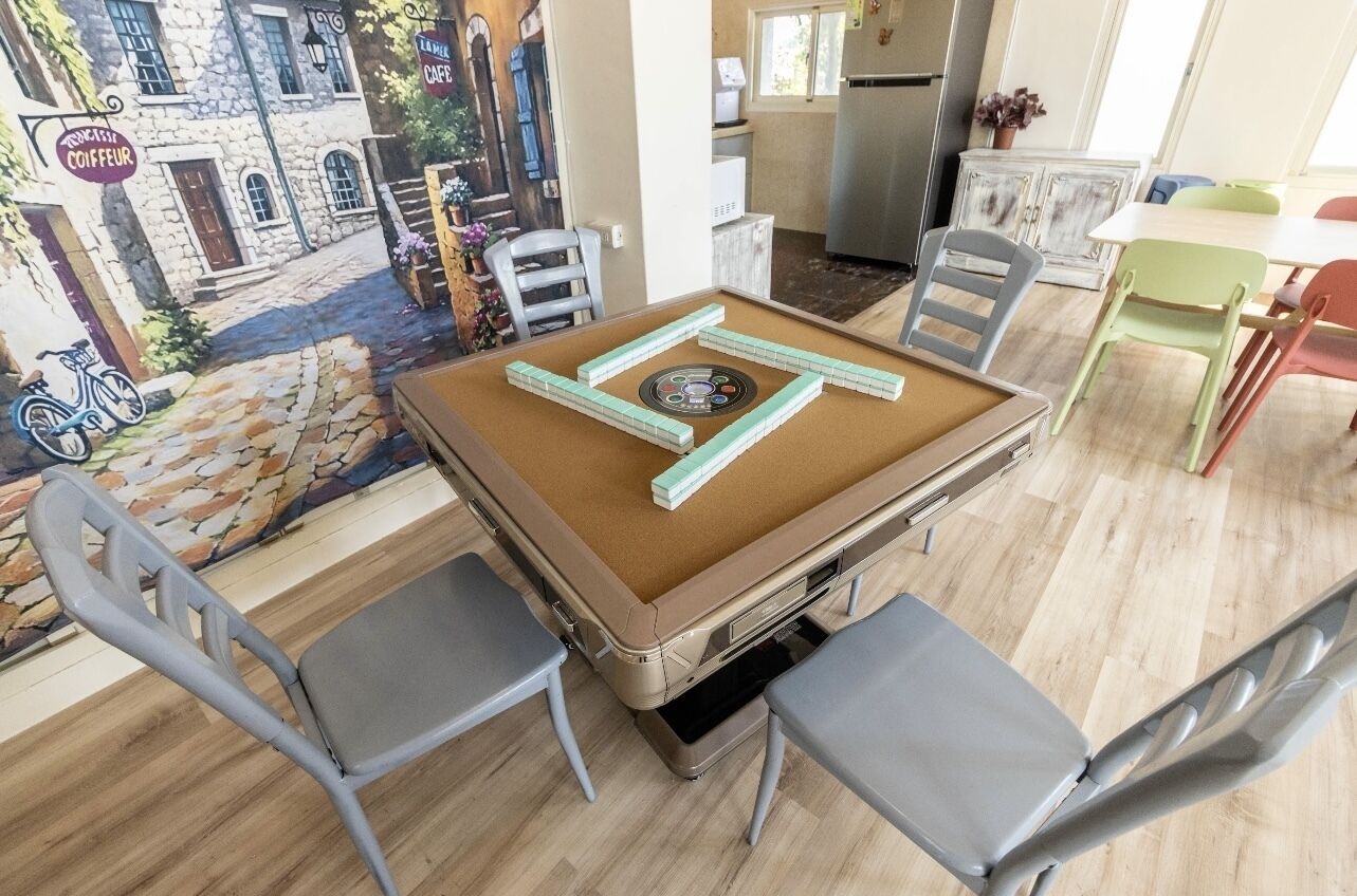 A cozy room with a pool table, comfortable chairs, and a mural of a street scene.