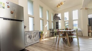 Una cocina con un refrigerador de acero inoxidable, un armario de madera rústica y un comedor con una mesa redonda y sillas coloridas.