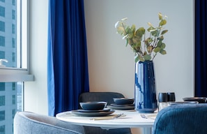 A dining table with a vase of green leaves, a bowl, and a cup.
