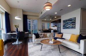 A modern living room with a white sofa, a coffee table, and a dining area with a table and chairs.