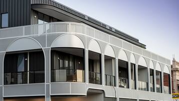 A modern building with a curved facade, large windows, and a balcony area.