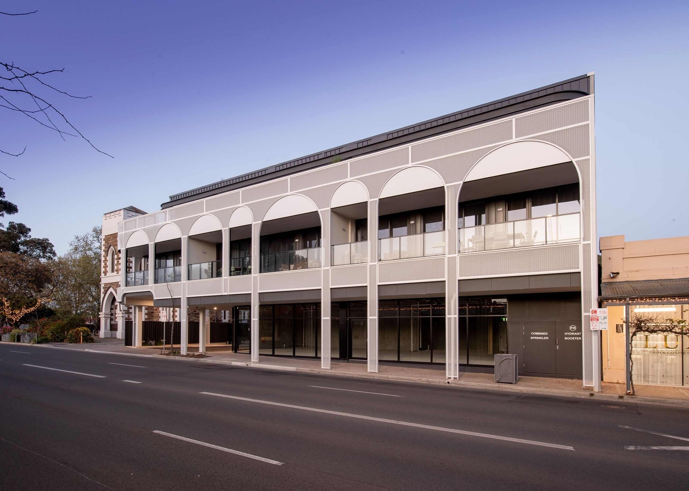 A modern building with a flat roof, multiple balconies, and large windows.