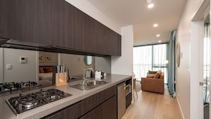 A modern kitchen with dark cabinetry, stainless steel appliances, and a built-in oven. - Grow at Goodwood (Goodwood)