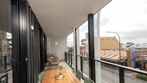 A balcony with a wooden table, chairs, and a bottle of wine. - Grow at Goodwood (Goodwood)