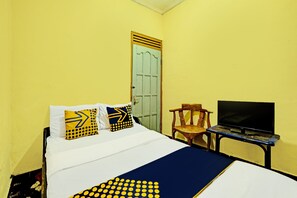 Een bed met wit en blauw beddengoed, een televisie op een bijzettafeltje en een stoel.