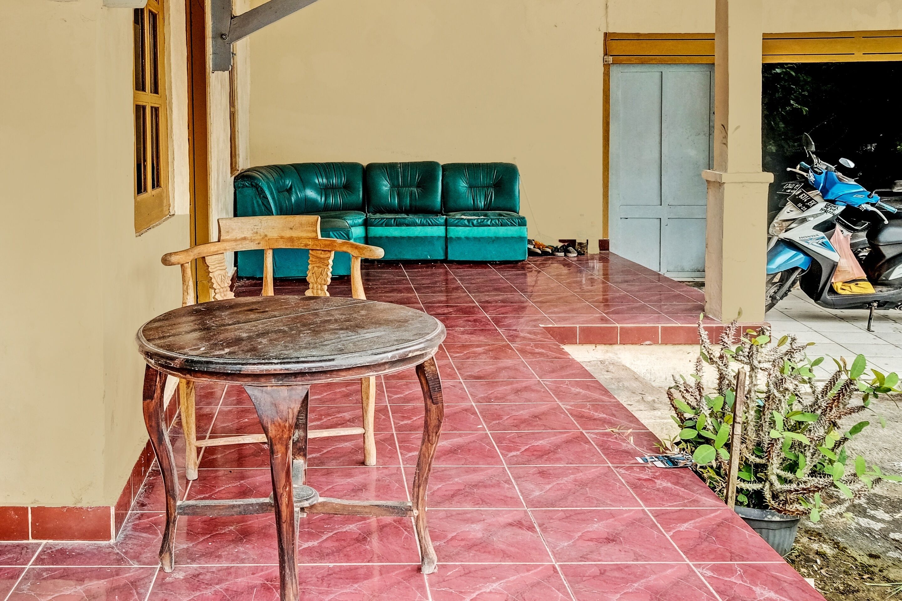 A room with a wooden table and chairs, a green sofa, and a tiled floor.