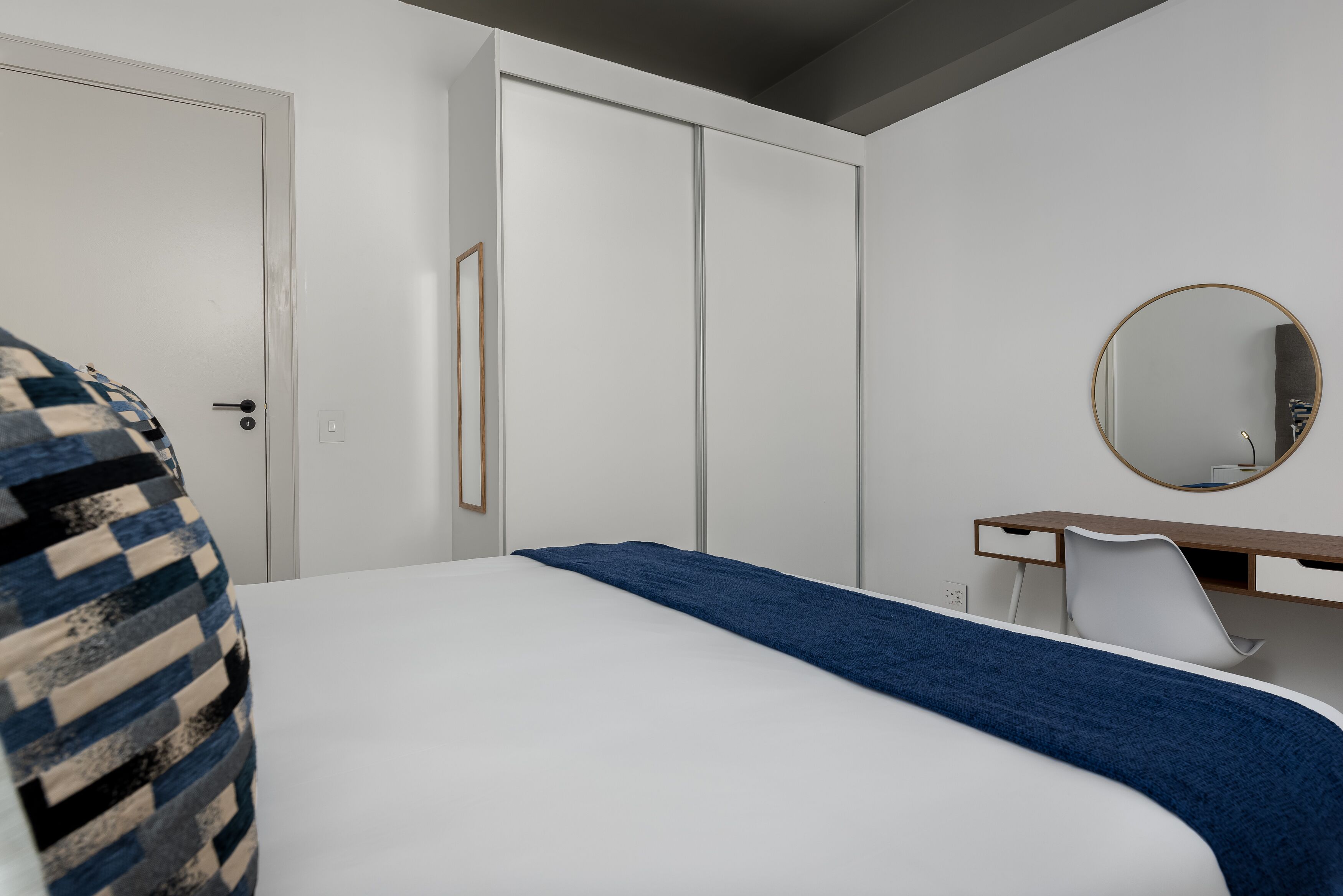 Ein Schlafzimmer mit Bett, Schminktisch, Spiegel und Tür.