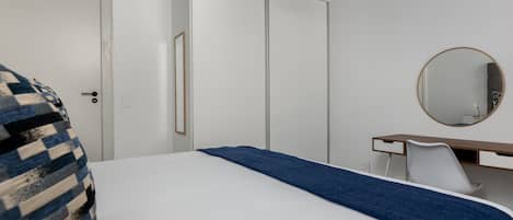 A bedroom with a bed, a dresser, a mirror, and a door.