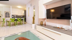A modern kitchen with a dining area, a large flat-screen TV, and a small pool area. - Designer, fully equipped APT, just off Tower Road (Tas-Sliema)