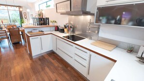 Een moderne keuken met witte kasten, een zwarte inductiekookplaat en een roestvrijstalen afzuigkap.