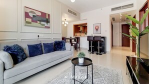 Un salon moderne avec un canapé gris, une table basse ronde et un coin repas à l’arrière-plan.