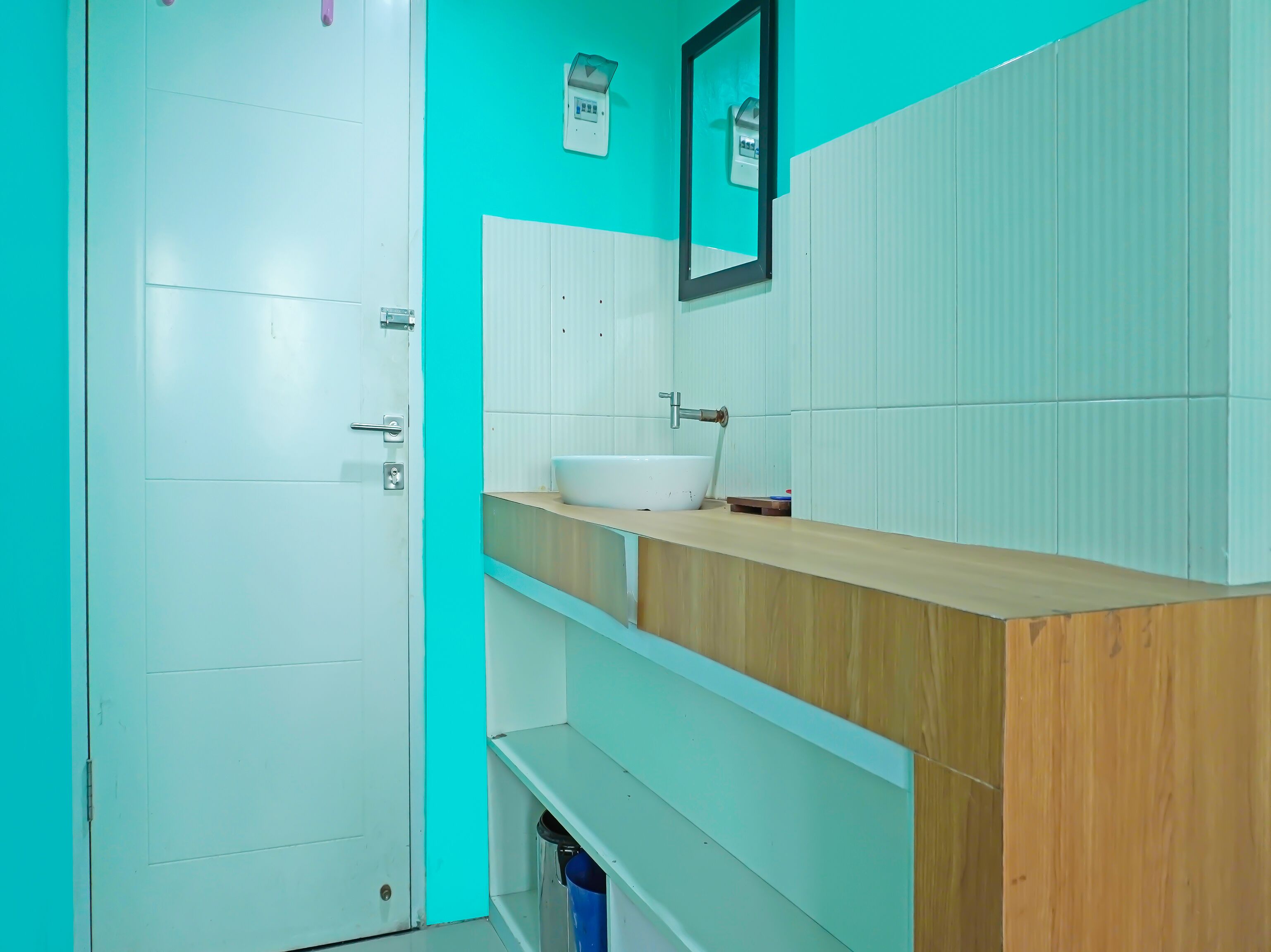 A bathroom with a white door, a sink, and a mirror on the wall.