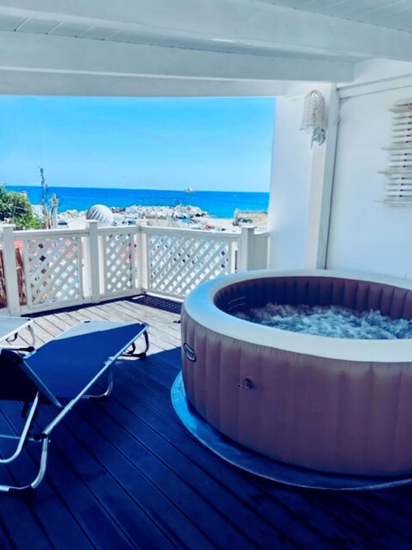 A hot tub on a wooden deck with a view of the ocean.