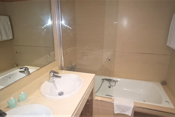 A bathroom with two sinks, a bathtub, and a large mirror.