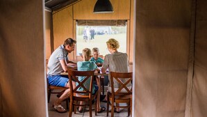 A family dining inside a tent-like structure with a view of an outdoor area.