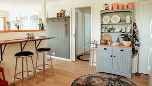 A kitchen with wooden stools, a bar counter, and a cabinet with dishes. - Luxury Couples' Retreat Beside the Beautiful Barwon River (Highton)