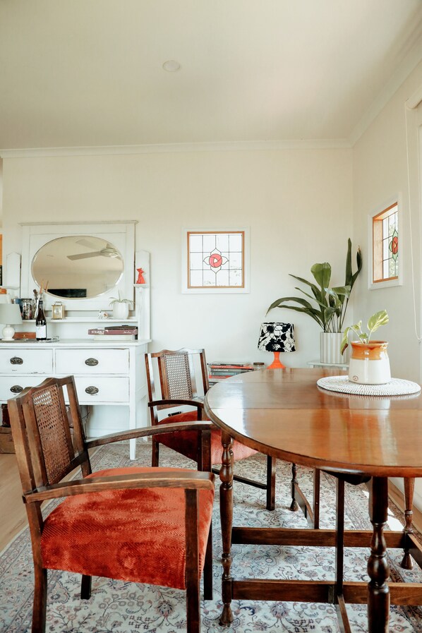 Un coin repas avec une table en bois, des chaises, une commode blanche et un miroir.