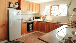 A kitchen with wooden cabinets, a refrigerator, a microwave, and a sink. - Luxury Couples' Retreat Beside the Beautiful Barwon River (Highton)