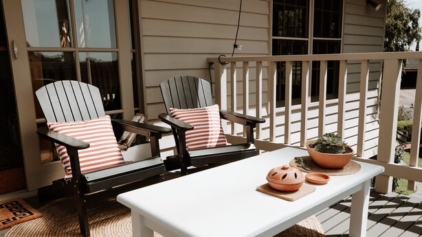 A porch with two Adirondack chairs, a white table, and a potted plant. - Luxury Couples' Retreat Beside the Beautiful Barwon River (Highton)