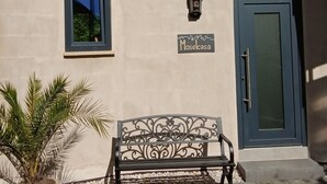 A building facade with a sign reading "Moselcasa," a window, a door, and a bench with a potted plant beside it.